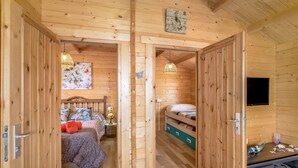 A wooden interior with a bed, bedside table, lamp, and a wall-mounted TV. - Vacation Home 'Finca Mariposa' with Sea View, Garden & Wi-Fi (Adeje)