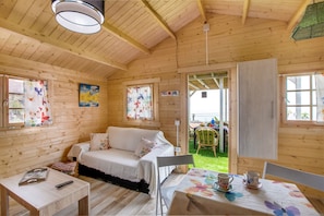Une cabane en bois avec un canapé, une table avec des tasses et une chaise.