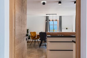 A modern kitchen with a wooden countertop, two chairs, and a window with curtains.