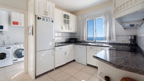 A kitchen with white cabinets, a dishwasher, a microwave, and a window with a view.