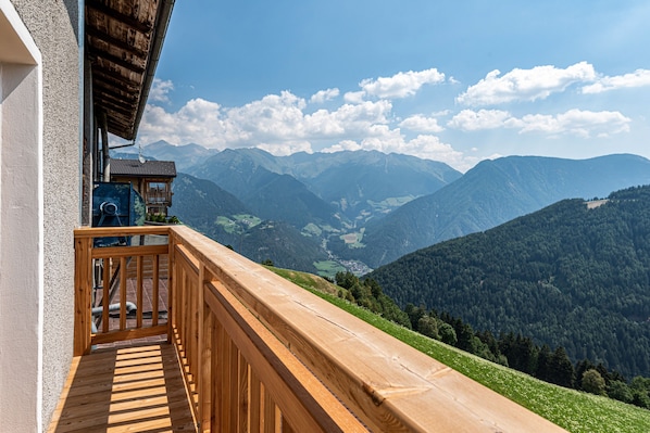 Un balcon en bois offrant une vue sur les montagnes et un ciel dégagé.