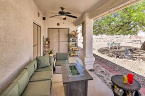 Een overdekt terras met een bank, een bijzettafeltje en een kleine tuin.