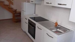 Une cuisine avec des meubles blancs, une cuisinière noire et un évier.