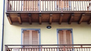 Un bâtiment à deux étages, doté de balcons en bois, d’une façade bleue et beige, et d’une entrée au niveau du sol.