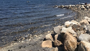A rocky shoreline with clear water and distant mountains.