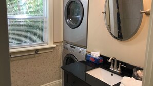 A laundry room with stacked washers and dryers, a sink, and a mirror.