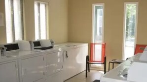 A laundry room with a washing machine, dryer, and stacked laundry baskets. - Top floor, one bedroom condo on the lake! 
 Perfect for a couples weekend. (Osage Beach)