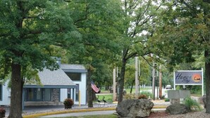A building with a sign reading "Heron Bay" and a small American flag. - Top floor, one bedroom condo on the lake! 
 Perfect for a couples weekend. (Osage Beach)
