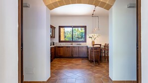 Une cuisine avec des meubles de rangement en bois, une fenêtre et un sol carrelé.