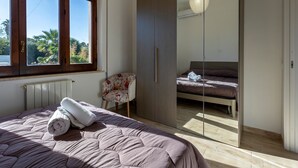Une chambre à coucher comprenant un lit, une chaise, une armoire et une fenêtre donnant sur un paysage verdoyant.