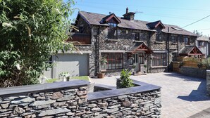 A stone building with multiple windows and a stone wall in the foreground.
