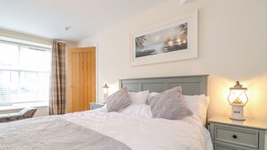 A neatly made bed with a patterned bedspread, a headboard, and two bedside tables with lamps.