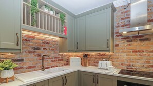 A kitchen with a brick wall, a white sink, a toaster, and a dish rack.