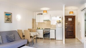 Un espai vital compacte amb cuineta, zona de menjador i sofà.