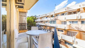 Ein Balkon mit rundem Tisch und Stühlen, mit Blick auf ein Wohngebäude.