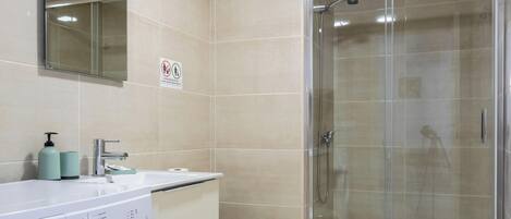 A modern bathroom with a washing machine, toilet, and glass-enclosed shower.