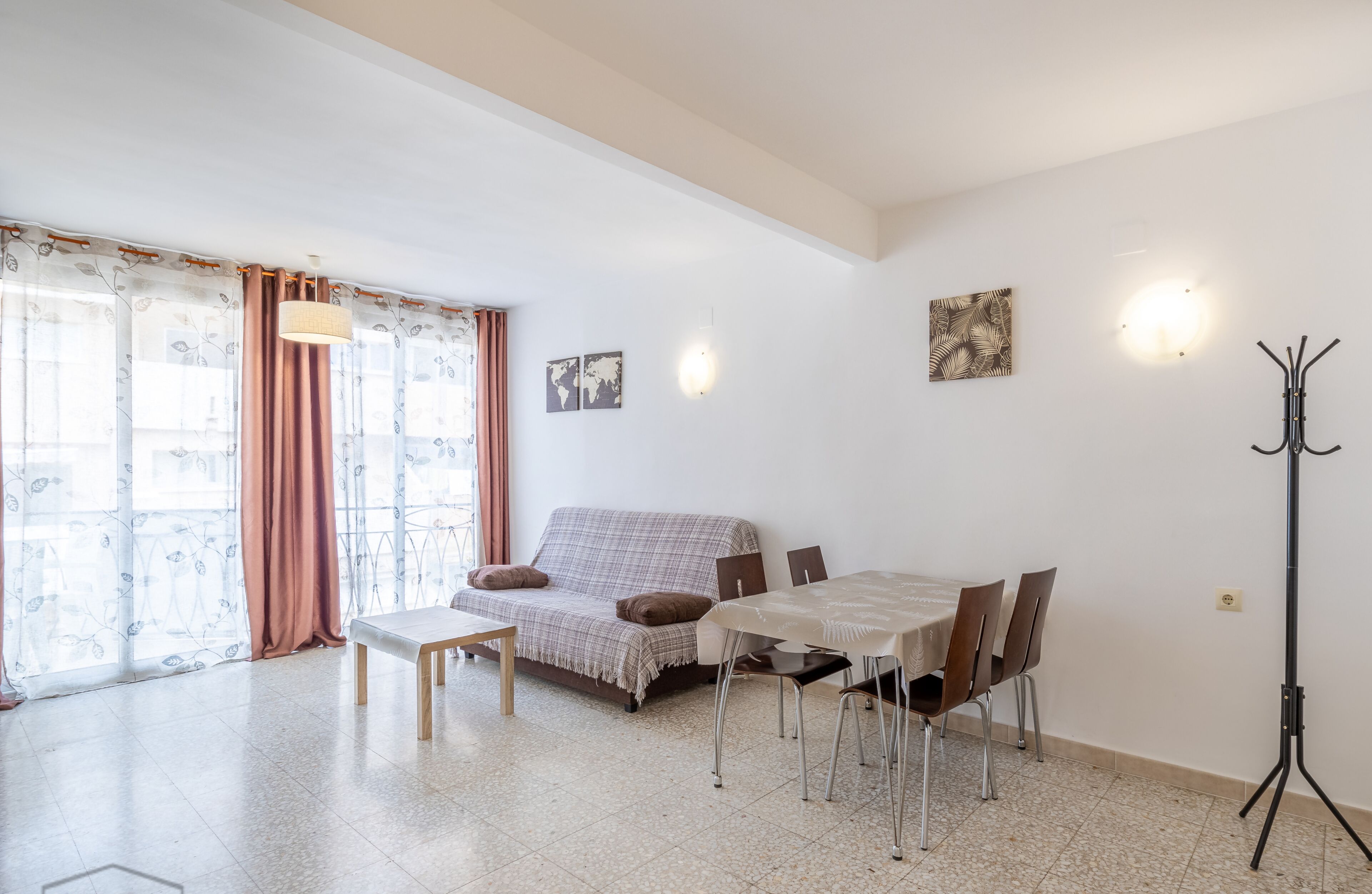 A living room with a sofa, dining table, chairs, a coat rack, and a lamp.