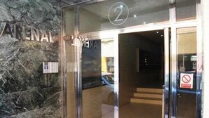L’entrée d’un hôtel, avec un mur de marbre, une porte en verre portant le numéro 2 et un panneau indiquant qu’il est interdit de se garer.