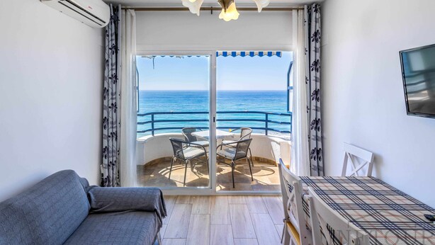 Un balcon avec vue sur la mer, un canapé, une table avec des chaises et un appareil de climatisation.
