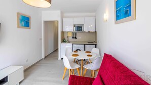 Un apartamento moderno con comedor, cocina y un sofá rojo.
