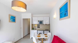 A modern apartment with a dining area, kitchen, and a red sofa.