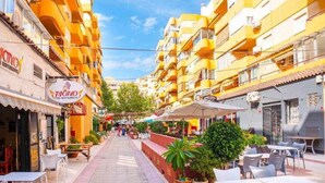 Eine Straße mit gelben Häusern, Außenplätzen und einem thailändischen Restaurant.