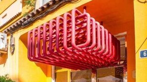 Ein Gebäude mit einer gelben Fassade, einer roten Tür und einem Glastür-Eingang.