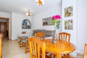 A dining area with a wooden table and chairs, a vase with flowers, and a mirror on the wall. - Inftour Medici Apartamento (Calp)