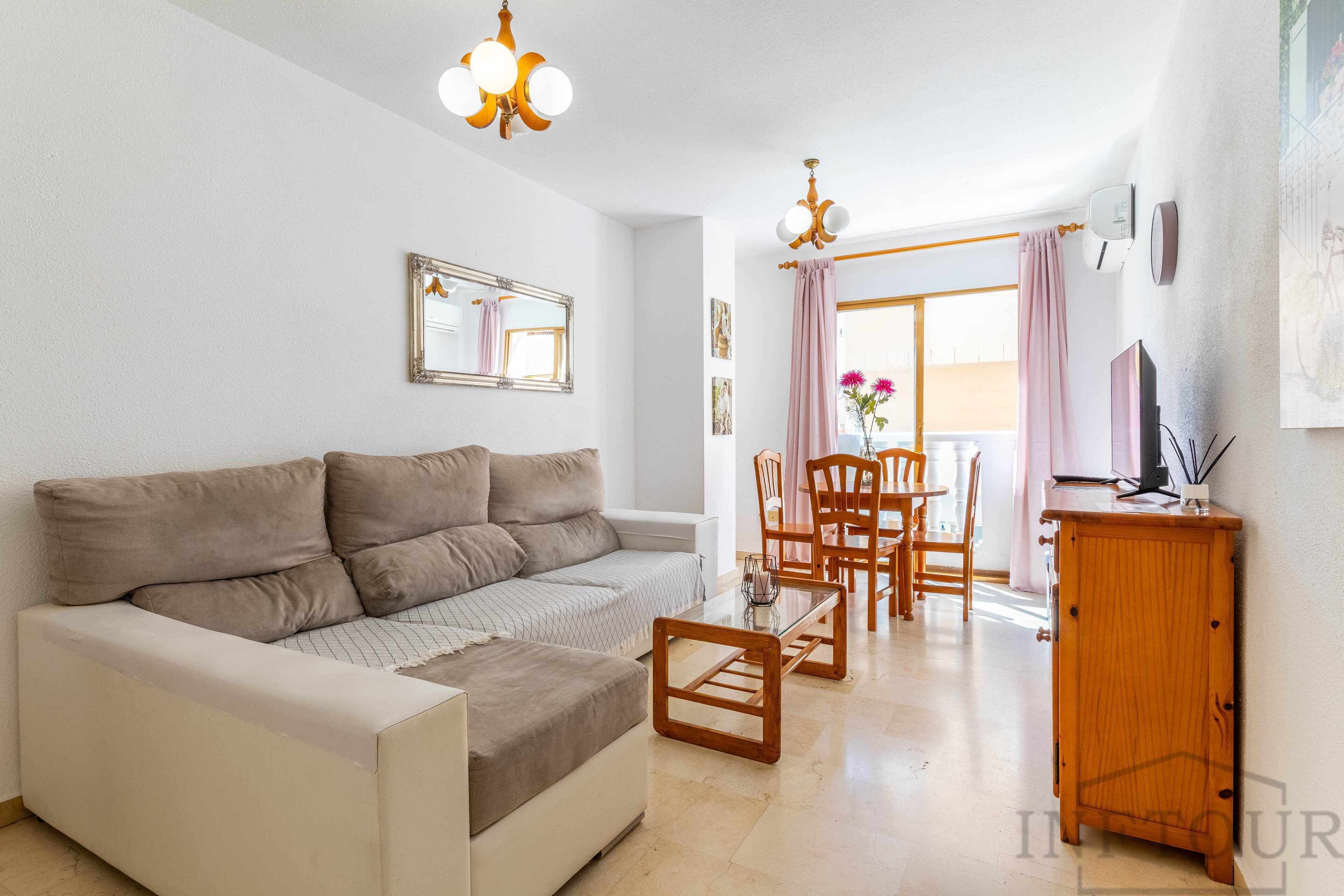 A modern living room with a sofa, a coffee table, and a dining area with chairs and a table.