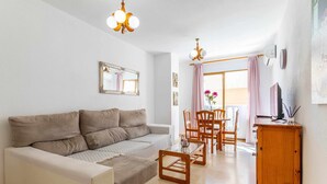 A modern living room with a sofa, a coffee table, and a dining area with chairs and a table.
