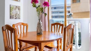 A dining area with a round wooden table and six chairs, a vase with flowers, and two framed pictures on the wall.