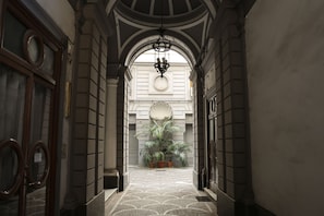 A corridor with a patterned floor, a large mirror, and a potted plant.