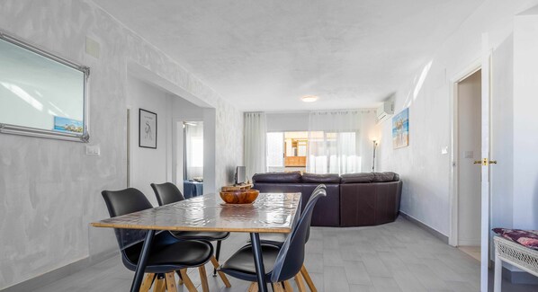 A modern dining area with a large table, chairs, and a brown bowl centerpiece.