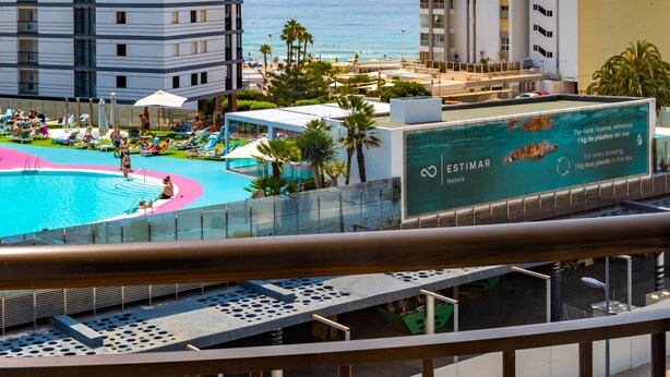 Un hotel con piscina, vista sulla spiaggia e diversi piani.