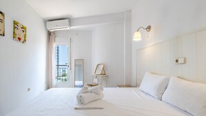 Una camera d'albergo con un letto rifatto, un comodino, uno specchio e una finestra con vista.