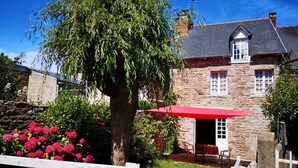 A stone house with a red umbrella, a stone wall, and pink flowers. - Charming townhouse, 10 minutes walk from the beach! (Erquy)