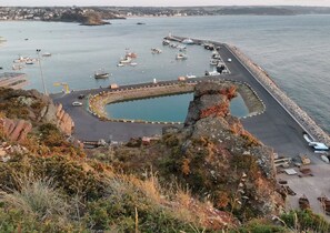 Un port côtier avec des bateaux, une jetée et une côte rocheuse.