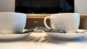 Dos tazas blancas sobre platillos, con una bolsita de té en medio.