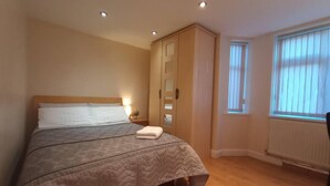 Un dormitorio con cama, armario, ventana y radiador.