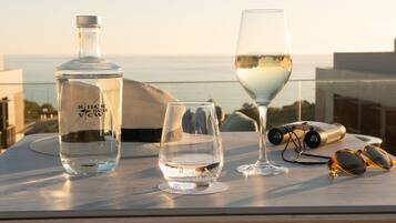 A table with a bottle, two glasses, binoculars, and sunglasses.
