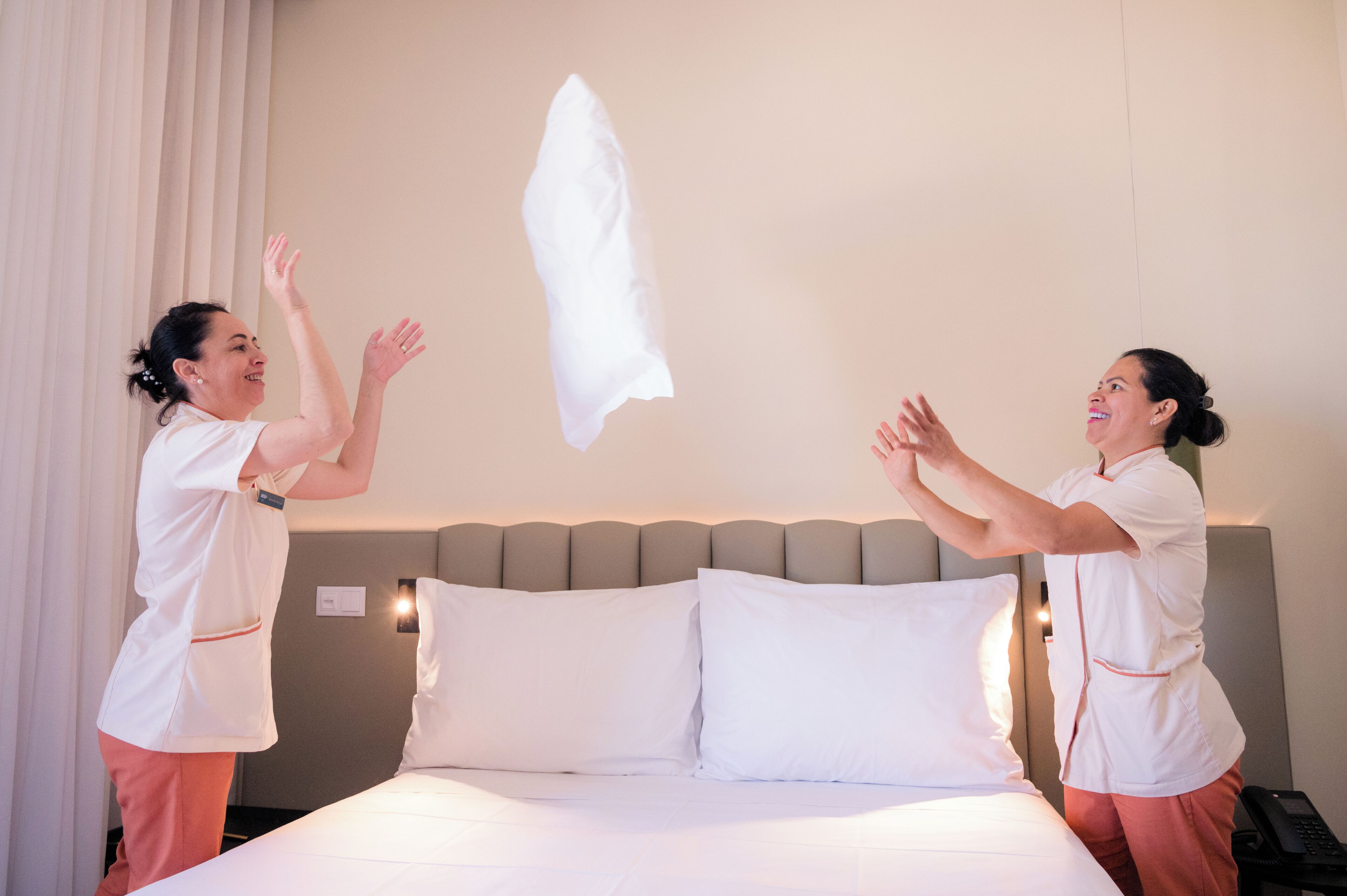 Camera d'albergo con un letto, cuscini e comodino con il telefono.