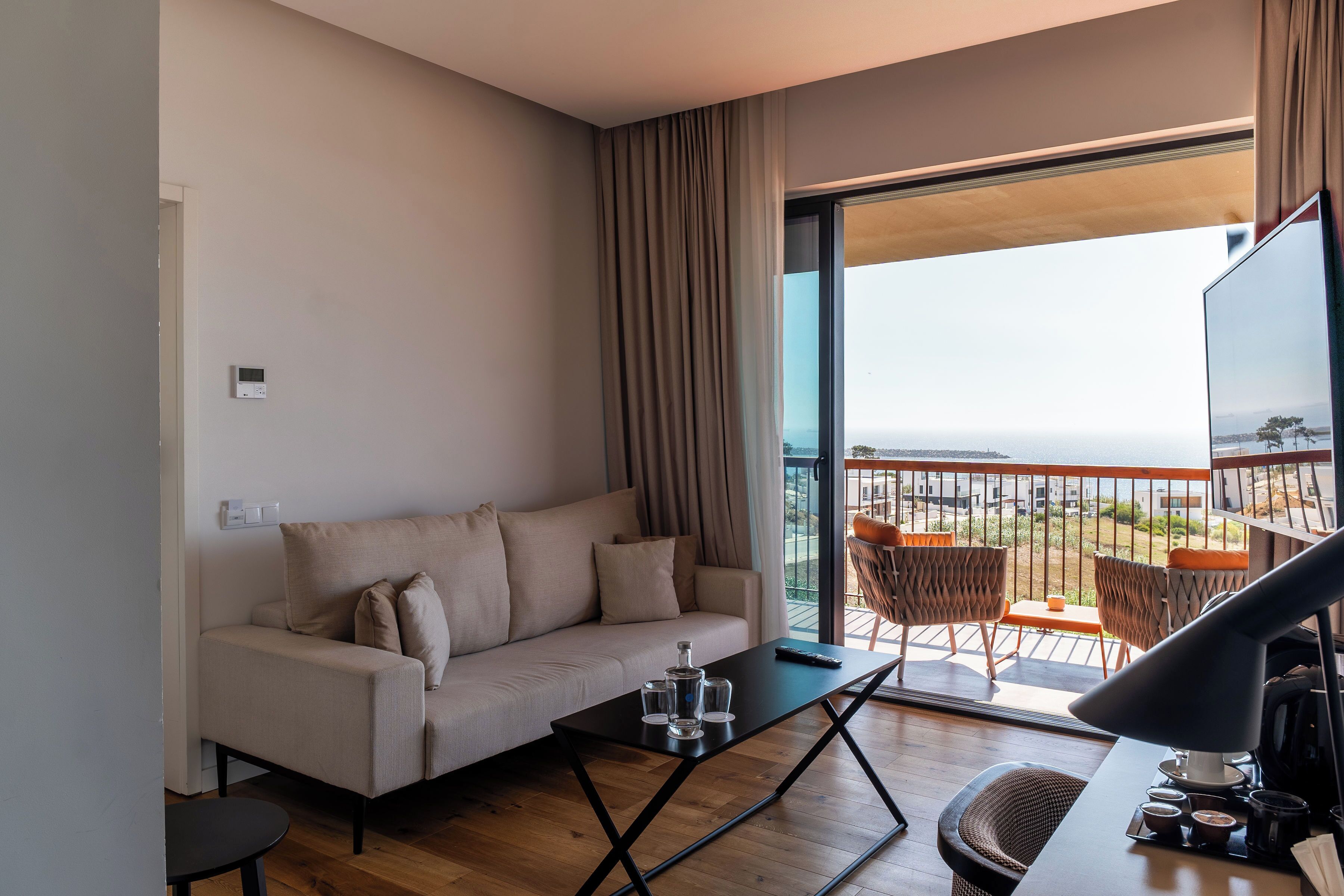 Un salon moderne avec un canapé, une table basse et un balcon aménagé avec des sièges d’extérieur.