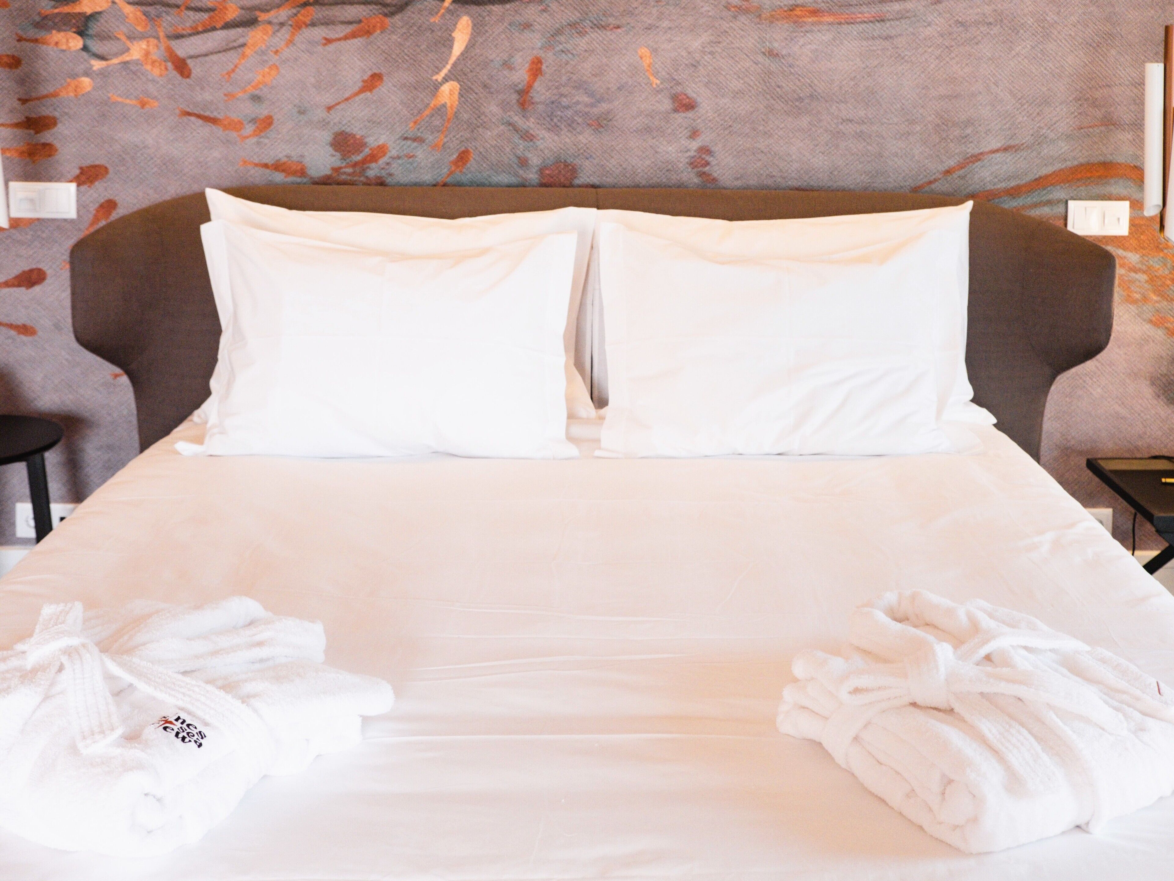 A neatly made bed with white linens and two towels placed on either side.