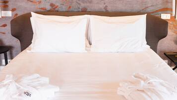 A neatly made bed with white linens and two towels placed on either side.