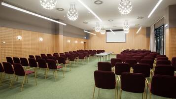 A conference room with rows of chairs, a projector screen, and modern lighting fixtures.
