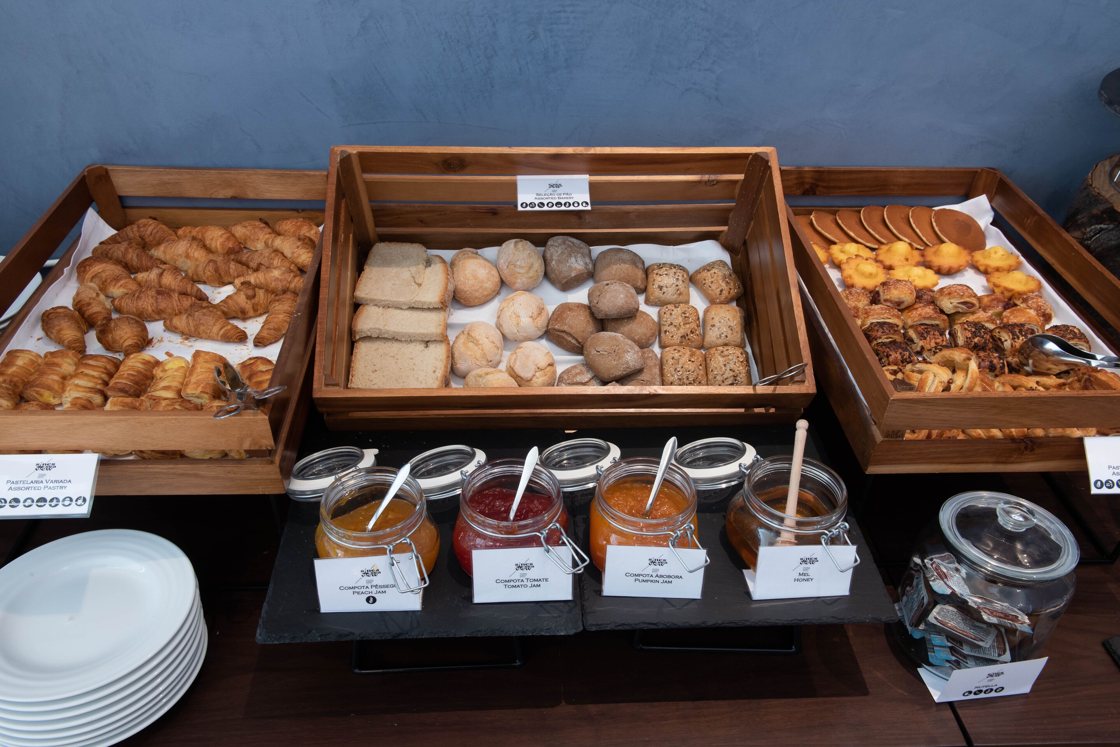 A breakfast buffet with various pastries, sandwiches, and condiments.