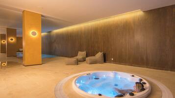 A spa area with a hot tub, lounge chairs, and a wooden wall.