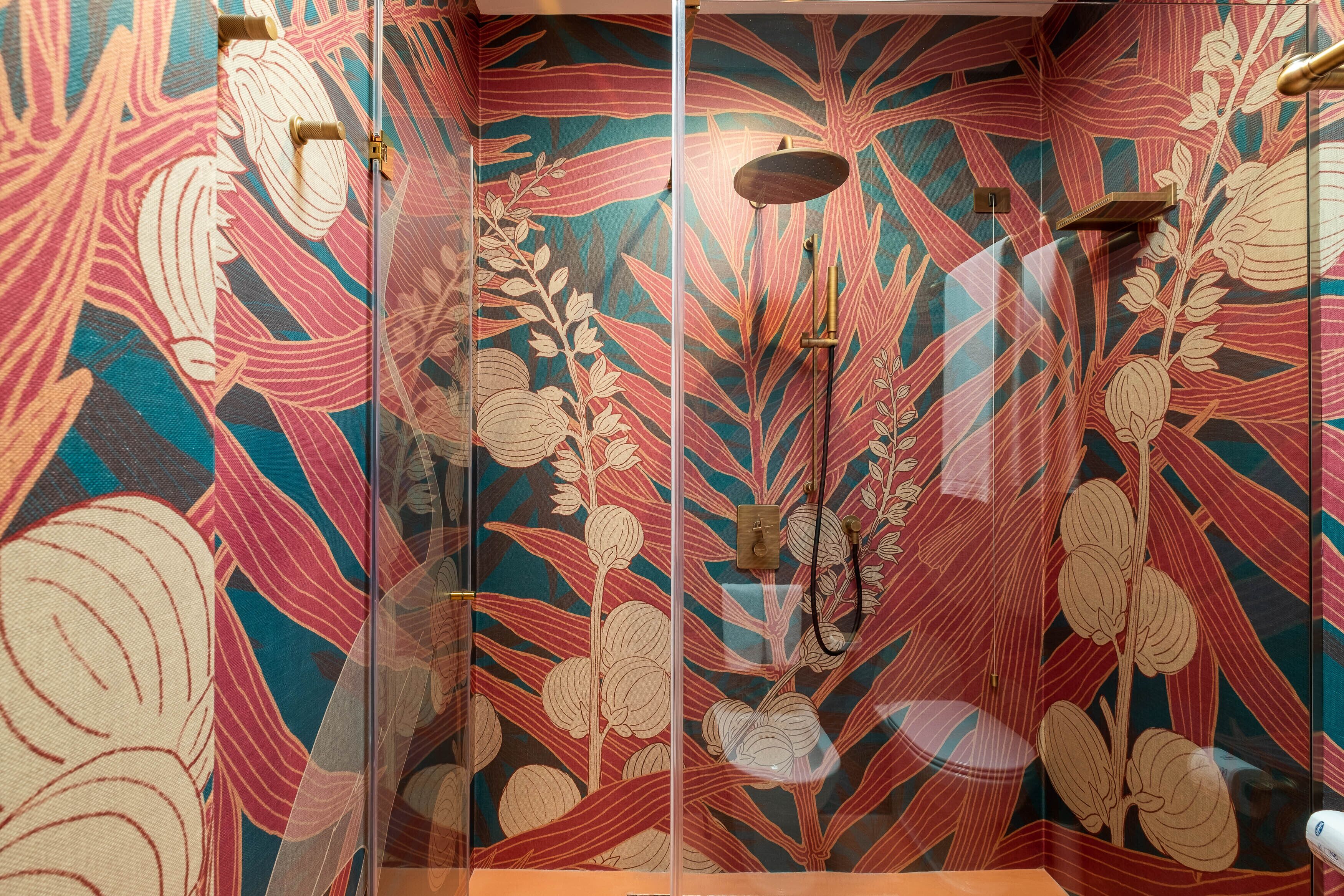 A bathroom with a floral wallpaper design, a shower area, and a towel rack.