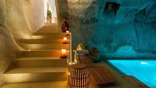 Un área de spa con una escalera de piedra, velas, un farol de madera y una piscina.