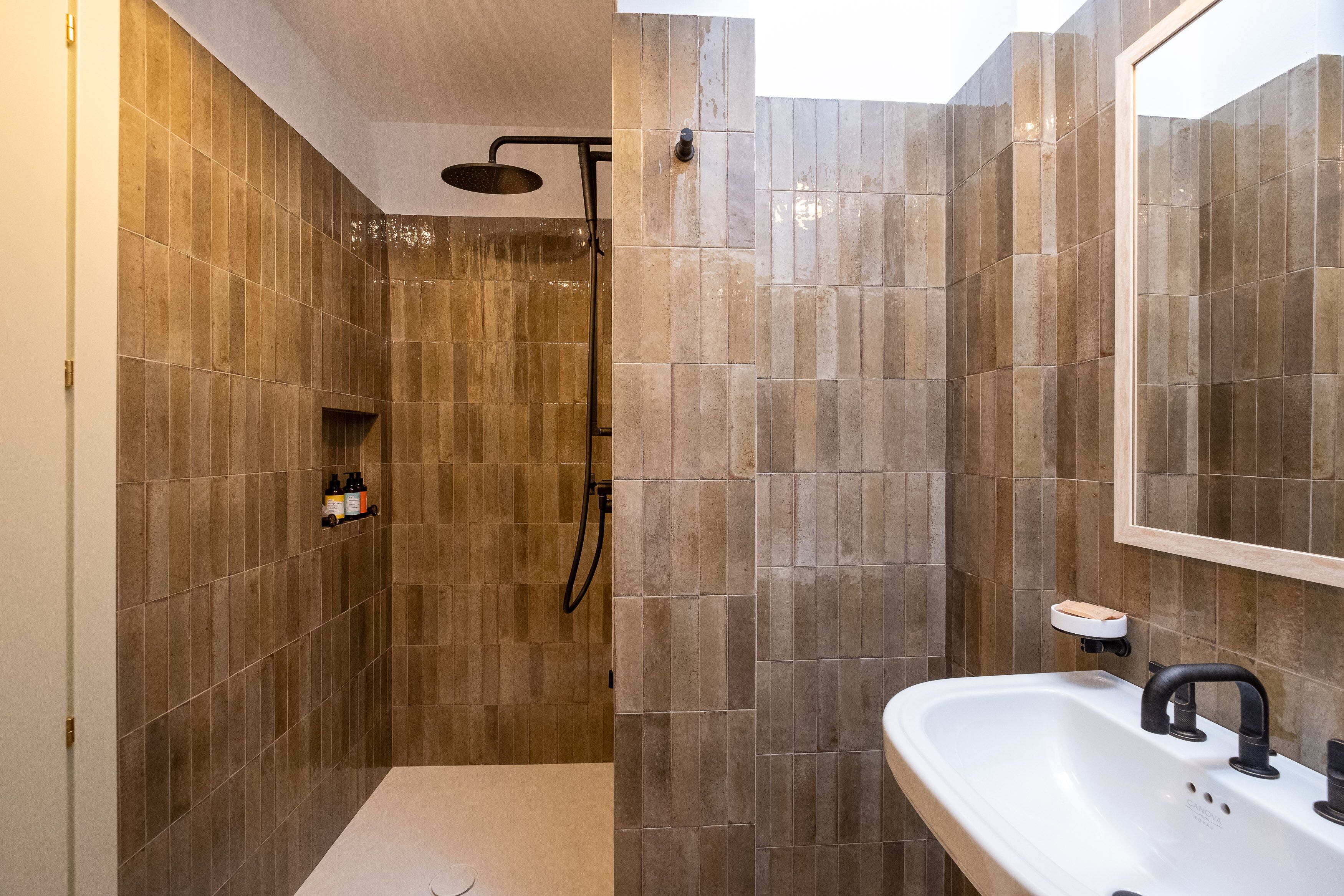 A modern bathroom with a shower, a sink, and a mirror.